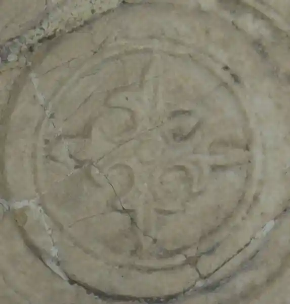 Fleur-de-lis solar cross inside a circle on a marble stone